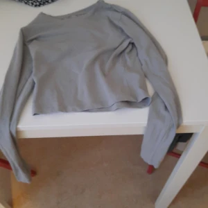 Grå croppad långärmad tröja - En enkel och stilren grå croppad långärmad tröja. Perfekt att matcha med höga jeans eller kjol. Mjuk och skön, passar till många olika outfits.