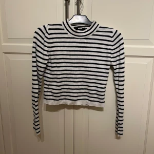 Randig ribbad tröja från BikBok - Säljer en svartvit randig ribbad tröja från BikBok i storlek M. Tröjan är croppad med långa ärmar och har en rund halsringning. 
