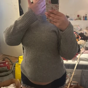 Grå stickad tröja från Lindex - Mysig grå stickad tröja från Lindex med hög hals och ribbade muddar. Perfekt för kyliga dagar och enkel att matcha med olika outfits. Klassisk modell med lång ärm och mjukt material. (Passar mig som har M-L