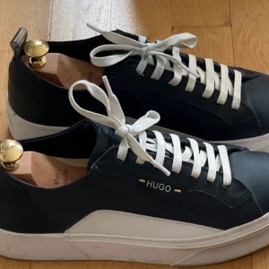 Hugo Boss herrsneakers i stl. 43  - Hugo Boss herrsneakers i stl. 43 i blåskinn med vita detaljer. Skorna har använts ett par gånger. Pris 1000kr plus porto.