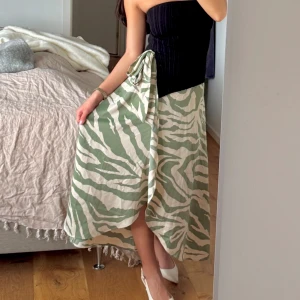 Omlottkjol från Monki - Säljer denna fina omlottkjol i satin med knytning i midjan, kjolen är endast använd 1 gång och är som helt ny!🌷