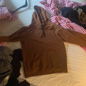 Brun hoodie från Farcco -  Oanvänd Säljer en brun hoodie från Farcco med klassisk känguruficka och justerbar huva med snören. Perfekt för en avslappnad stil och enkel att matcha med jeans eller mjukisbyxor.