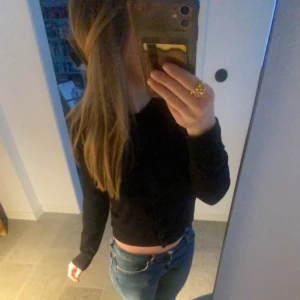 Svart croppad kofta - Säljer en svart croppad kofta med långa ärmar och knappar framtill. Perfekt att styla med jeans eller kjol.
