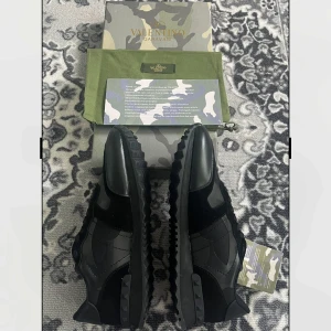 Svarta sneakers Valentino Garavani - Säljer ett par svarta Valentino Garavani sneakers med snygga detaljer och mönstrad sula. Skorna har snörning. Kommer med originalkartong och dustbag med camouflage-mönster. Strl 46 men passar mindre strl som 44/45