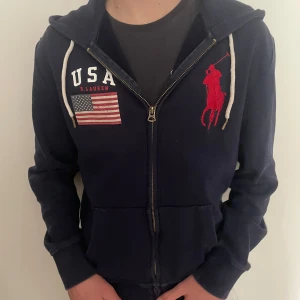 Sällsynt & Exklusiv Ralph Lauren hoodie!  - Väldigt sällsynt och exklusiv Ralph Lauren Hoodie. Hoodien är marinblå med dragkedja och två stora tryck. Riktigt snygg och väldig unik då den inte går att hitta. Storlek: S, Skick: 10/10. Köpt begagnad men oanvänd då den var för liten… Kontakta vid frågor eller funderingar! PRIS KAN SÄNKAS VID SNABB AFFÄR!