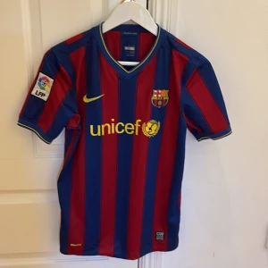 FC Barcelona hemmatröja - Klassisk FC Barcelona fotbollströja med blå och röda vertikala ränder, officiellt klubbmärke och Nike-logga på bröstet. Unicef-tryck på framsidan och LFP-märke på ärmen. Kortärmad modell i lätt och ventilerande material.