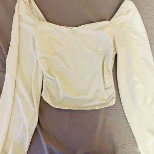 Vit långärmad topp - Säljer en vit långärmad topp med puffiga ärmar. Toppen har en figurnära passform 🌸.