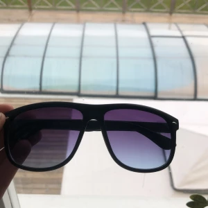 Svarta solglasögon från Kayoba - Säljer ett par svarta solglasögon från Kayoba med rektangulära bågar och lila-tintade glas. Glasögonen har en klassisk design och passar perfekt för soliga dagar. Riktigt stiliga och liknar Rayband boyfriend! Pris kan diskuteras!