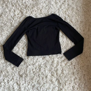 Svart långärmad topp från Gina Tricot - Säljer en svart långärmad topp från Gina Tricot. Toppen har en rundad ringning där bak och är figurnära i modellen. Den är Stt tyngd där fram och öppen där bak.  Perfekt att matcha med jeans eller kjol för en enkel och stilren look. Orginalpris ca 200kr. Pris kan diskuteras 