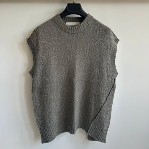 Adnym grå stickad väst - Säljer en grå stickad väst från Adnym med grov ribbstickad halsringning och nederkant. Västen har en asymmetrisk form och en diskret söm som löper snett över plagget. Generös oversized passform som passar någon som vanligtvis bär S-M. Påminner om Ann Demeulemeester, Rick Owens, Yohji Yamamoto, Comme des Garcon, Undercover