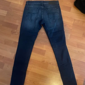Mörkblåa jeans tiger of Sweden 31/32 - Säljer ett par mörkblå slim fit jeans med klassisk femficksdesign. Byxorna har normal midja och raka ben med lätt tvättade detaljer framtill. Perfekta för dig som gillar en smalare passform. Storlek 31/32.