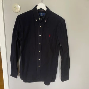 Ralph lauren skjorta - En mörk blå Ralph lauren skjorta. Den är i storlek S och i mycket bra skick. Hör av er vid intresse!!