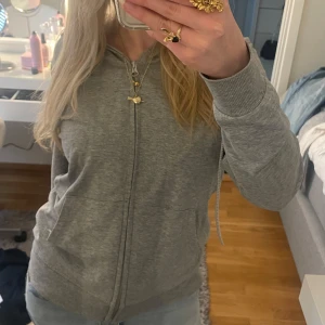 Grå zip-hoodie från Johaug - Grå hoodie med dragkedja från Johaug. Enkel och stilren design med liten logga på vänster sida