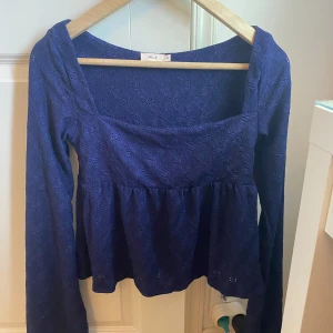 Mörkblå spetsblus med lång ärm -  Blusen är i spetsmaterial och har en lätt utställd nederdel som ger en söt siluett. Perfekt att styla med jeans eller kjol. Storlek xs (slutsåld på hemsidan) ☺️ Aldrig använd då den va för liten för mig. Men superfin till sommaren när man är lite brun🥰