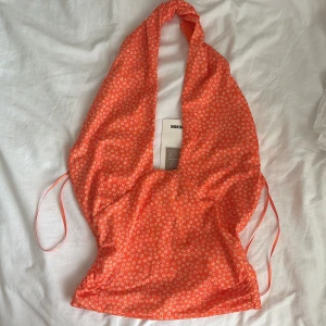 Orange blommig omlottopp från bikbok - Säljer en orange omlottopp från Bikbok med små vita blommor. Perfekt för varma dagar och somrig stil! Ny med prislapp!