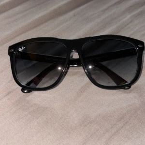 Ray ban solglasögon  - Klassiska svarta solglasögon från Ray-Ban med Wayfarer-inspirerad form. Tillverkade i blankt plastmaterial med mörka glas. Diskret Ray-Ban-logga på bågen och linsen. Perfekt accessoar för en stilren look.