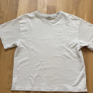 Beige basic t-shirt från Lindex - Enkel och stilren beige t-shirt från Lindex i mjuk bomull. Klassisk passform med rund hals och korta ärmar, perfekt till jeans eller shorts. 