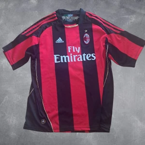 AC Milan retrotröja - Säljer en klassisk AC Milan matchtröja med Gattuso #8 på ryggen. Tröjan är röd och svart med breda ränder, Adidas-logga och Fly Emirates-tryck på bröstet. Korta ärmar och officiellt klubbmärke på bröstet. Perfekt för dig som älskar italiensk fotboll. Tröjan är 100% autentisk.