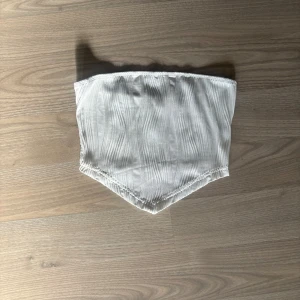 Vit bandeau tubtopp med struktur - Säljer en vit tubtopp med snyggt strukturerat tyg och spetsig nederkant. Toppen är aldrig använd🥰