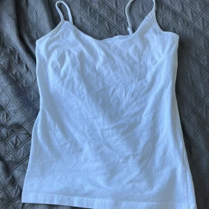 Vit linnetopp från 157, storlek M - Enkel och fräsch vit linnetopp från 157 med smala axelband. Tillverkad i mjuk bomull med lite stretch för extra komfort. Perfekt att styla med jeans eller shorts för en clean look.