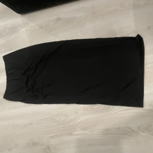 Svart långkjol i enkel stil - En stilren svart långkjol med rak passform. Kjolen är helt enfärgad och har en minimalistisk look som passar till många olika outfits. Perfekt för dig som gillar en clean och tidlös vibe.