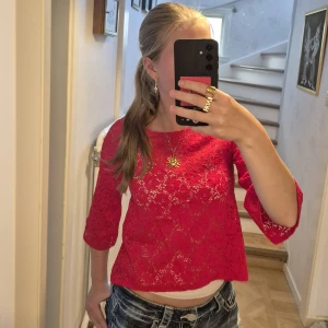 Röd spetsblus från Gina Tricot - Säljer en röd blus från Gina Tricot i genombruten spets med blommigt mönster. Modellen har trekvartsärmar och en något croppad passform framtill. Aldrig använd! Stl xs.