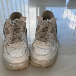 Nike Air Force 1 vita sneakers - Nike Air Force 1 sneakers i vitt skinn med perforerade detaljer på tån och sidorna.Perfekta för dig som gillar streetstyle och tidlös design. 