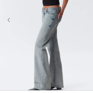 Wide ljusblå jeans från Weekday - Säljer ett par ljusblå jeans från Weekday med breda ben och slitna detaljer på både fram- och baksida. Klassisk femficksmodell med hög midja och bootcut-inspirerad passform. Jeansen är i mjukt denimtyg och har en snygg vintagekänsla.