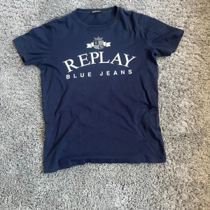 Mörkblå t-shirt från Replay - Snygg mörkblå t-shirt från Replay med tryck 'Replay Blue Jeans' i vitt på framsidan. Perfekt för en casual look. Kortärmad och tillverkad i mjukt material för extra komfort.