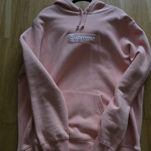 Supreme peach box logo - Obs f@k3! Supreme hoodie i färgen peach med broderad box logo på bröstet. Klassisk känguruficka, huva med snörning och mjukt bomullsmaterial. Perfekt för dig som gillar streetwear och vill sticka ut med en ikonisk tröja. 