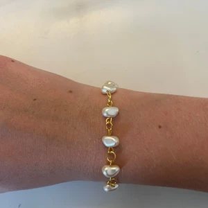 Armband med oregelbundna pärlor - Snyggt armband med oregelbundna vita pärlor på en tunn kedja i guld- eller silverfärg. Kedjan är tunn och länkarna ger ett stilrent intryck, medan pärlorna ger en cool och unik look. Perfekt accessoar för att lyfta din outfit. Skriv vilken färg du vill ha eller skriv om du vill köpa båda. Om du trycker på löp nu så köper du EN inte TVÅ armband. 1 för 35kr och båda för 65kr