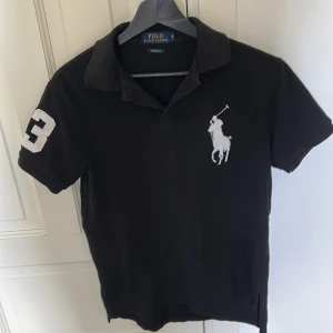 Svart pikétröja Polo Ralph Lauren S - Svart pikétröja från Polo Ralph(big pony) Lauren i bomull, custom fit. Klassisk krage, korta ärmar och stor vit logga på bröstet samt siffra 3 på ärmen. PRIS KAN DISKUTERAS 