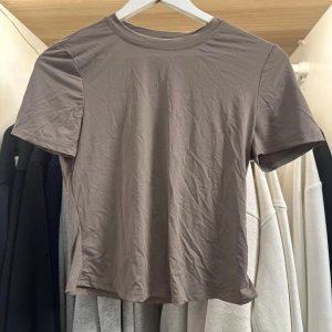 Brun kortärmad topp från SHEIN - En enkel och stilren brun topp från SHEIN i storlek M. Modellen är tight och croppad med rund halsringning och korta ärmar. Perfekt att matcha med jeans eller kjol för en clean look.