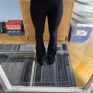 Svarta bootcut leggings i stretch - Svarta leggings med bootcut-snitt från C, i stretchigt och mjukt material. Hög midja och figurnära passform upptill som går ut i en lätt utsvängd benvidd. Perfekta för en chill och trendig look.