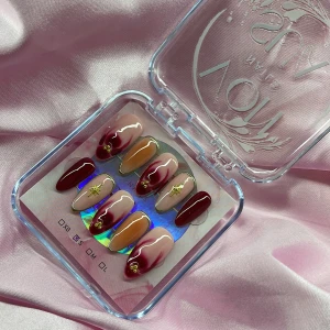CherryBlaze(S);Medium Almond - Snygga gelé press-on naglar i mandelform med vinröda, nude och rosa toner. Designen har trendy-mönster, guldiga detaljer och små stjärnor. Perfekt för dig som vill ha en trendig och unik look. Kommer i storlek S: 15 mm, 11,5 mm, 12 mm, 11 mm, 9 mm  