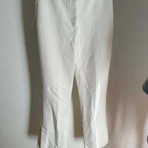 Vita bootcut byxor med slits - Snygga högmidjade kostymbyxor från Zara. De är något utsvängda nertill och med slits. Otroligt sköna!!! Jag upplever de inte genomskinliga. Passar perfekt i längd på mig som är 167cm. 