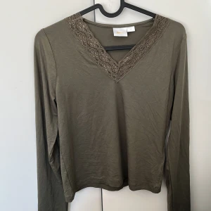 Olivgrön långärmad topp med spets - Olivgrön långärmad topp från Gina Tricot med snygg v-ringning och spetsdetaljer runt halsen. Mjuk och skön i bomullsmix. Original pris: 279kr säljer för: 70kr