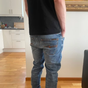Nudie Jeans Grim Tim blå jeans - Säljer ett par Nudie Jeans Grim Tim i klassisk blå tvätt med snygga slitningar och orange sömmar. Perfekta för både vardags bruk samt fest🍾🍾 tveka inte på frågor!👖priset går att diskutera vid snabb affär.