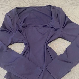 Mörkblå långärmad tröja topp med fyrkantig ringning - En stilren mörkblå långärmad topp med fyrkantig ringning. Toppen är figurnära och sydd i ett mjukt, stretchigt material som känns skönt mot huden. Perfekt att matcha med jeans eller kjol för en clean look.