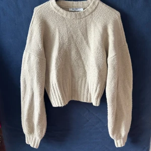 Beige stickad tröja NA-KD - Supermysig beige stickad tröja från NA-KD . Tröjan har rund hals, bred ribbad mudd nertill och vid ärmslut samt långa ärmar. Den mjuka ribbningen ger form runt midjan.