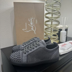 Gråa Christian Louboutin sneakers med nitar - Snygga grå sneakers från Christian Louboutin i mocka med nitar. Dem är nya och tyvärr för stora för mig. Hör gärna av er om mer info eller intresse☺️ Ny pris 12800 säljer för 12000