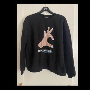 Svart sweatshirt från Monki med print - Cool svart sweatshirt från Monki med ett stort print av en hand och texten 'Boys be Whatever' på framsidan. Tröjan har rund hals, långa ärmar och en relaxed passform. 