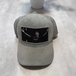 Grå Velvet Keps Från Wristwear - 🧢 Grå keps från Wrist Wear – Bellingham-motiv Stilren grå keps i mockaliknande material med svart mesh baktill. Tryck framtill föreställande Jude Bellingham. ✅ Skick: Mycket bra ✅ Justerbar passform 💸 Pris: 149 kr  📩 Skicka DM vid frågor eller intresse!