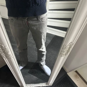 Grå jeansbyxor - Säljer ett par grå dsquared jeans med slitningar. Byxorna har en normal passform och är perfekta för en avslappnad stil. Byxorna har knappt används och har inga defekter. Skriv för fler bilder! Pris går att diskuteras.