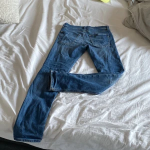 Blå jeansbyxor från Replay - Säljer ett par klassiska blå jeansbyxor från Replay med raka ben och snygga detaljer på bakfickorna. Byxorna har slim passform och är perfekta för dig som gillar en tidlös jeansstil. Märket Replay syns tydligt på insidan. Storleken är 12 år men går att använda ända tills 160 nypris ca 800