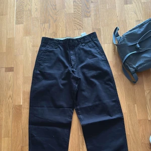 Svarta grova chinos med bred passform - Säljer ett par svarta chinos med klassisk design och normal passform. Byxorna har hällor för bälte, snedställda fickor fram och stängs med dragkedja och knapp. Perfekta för en stilren och enkel look.