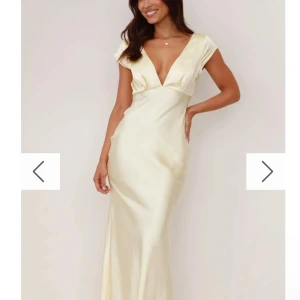 Gul  balklänning  - Elegant champagnefärgad och gul  långklänning i satin med v-ringad design. Klänningen har korta ärmar och en smickrande passform som ger en lyxig känsla. Perfekt för speciella tillfällen. Ny med pris lapp 