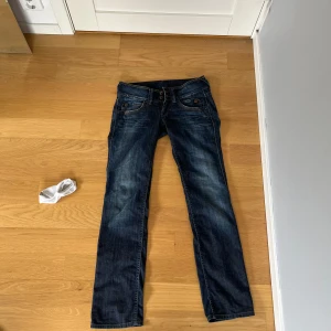 Blå jeans från Pepe Jeans - Snygga blå jeans från Pepe Jeans med klassisk femficksdesign och dekorativa sömmar på bakfickorna. Jeansen har en låg midja och en straight passform, perfekta för en avslappnad stil. Inte kommit till användning pga att de varit för stora, står otydligt men är size 27 i midjan