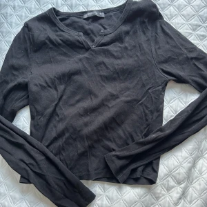 Svart långärmad topp från FS Sister - Säljer en svart långärmad topp från FS Sister. Toppen har en enkel design med en liten v-ringning och är tillverkad i bomull. Perfekt för en stilren look.