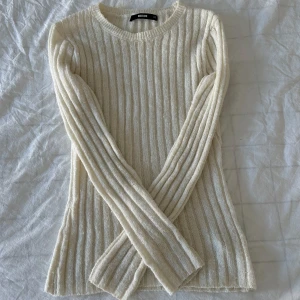 Ribbad vit stickad tröja  - Säljer en ribbad, vit stickad tröja från Bik Bok. Tröjan har lång ärm, rund halsringning och är figurnära i modellen. 